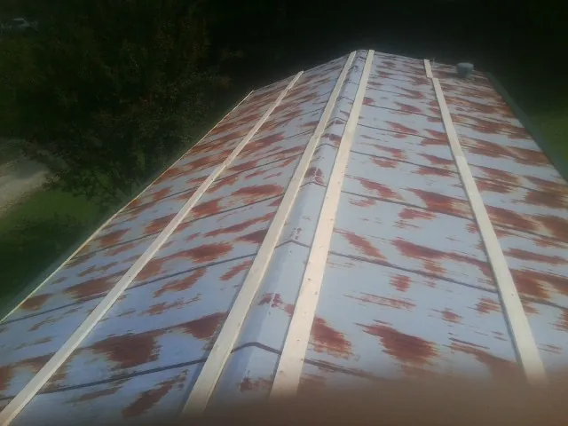 Rusted metal roof panels with new wood purlins before replacement — Storm Damage Roof Repair in Elliott by Roofing Brothers