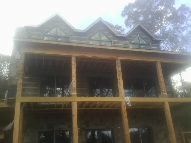 Dormers and porch framing on a large log home under construction — Roof Coating work by our crew in Elliott