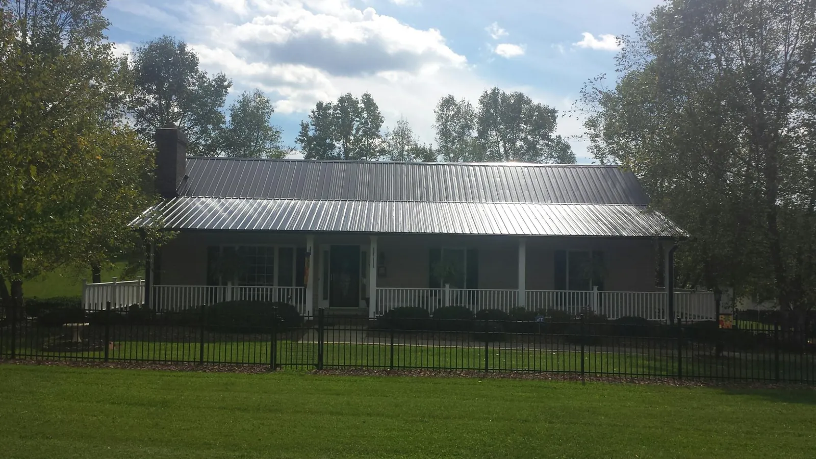 Gray metal roof on a brick ranch with a full width front porch — Gutter Guard Installation work by our crew in Elliott